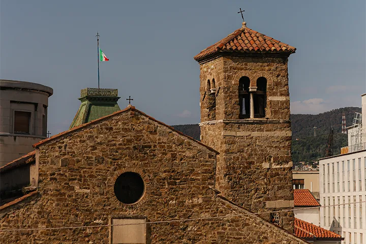 Kyrka i sten med klocktorn och tegeltak i en italiensk stad